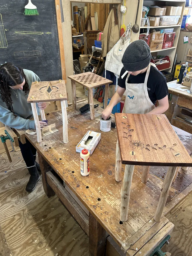 Middle school student woodworking in the shop, hand-carving decorative details into a wooden box at a traditional workbench