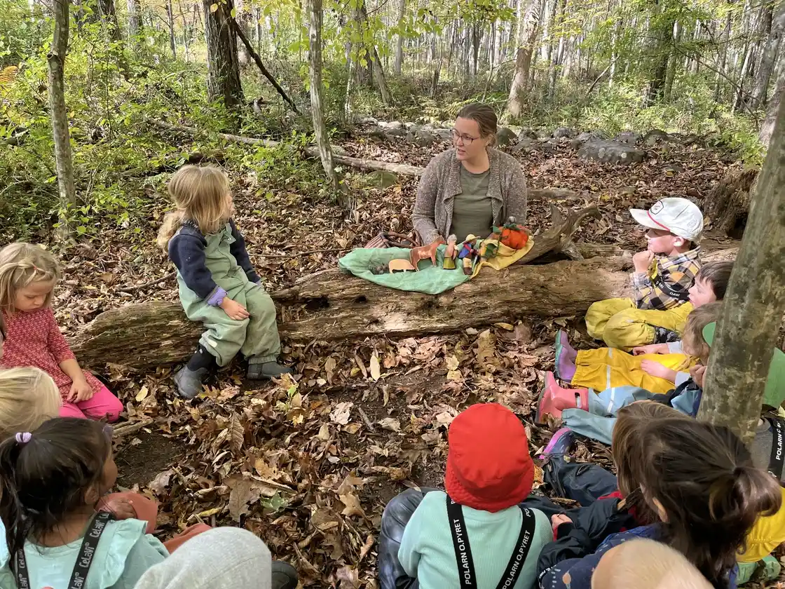 Teacher leading a lesson with wooden figures in the forest