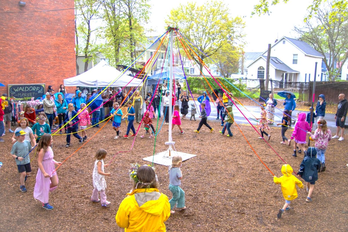 Children dancing around a Maypole on the school field