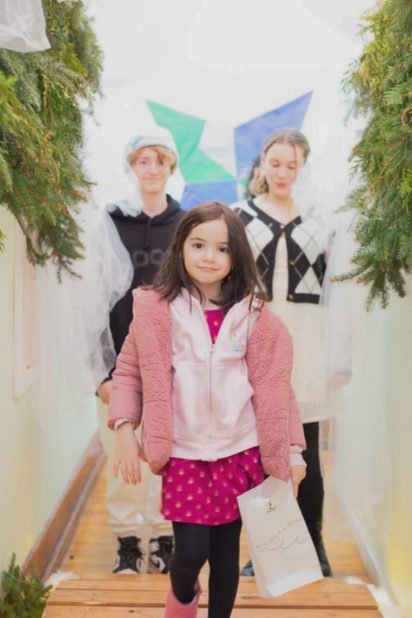 Students standing before a painted mural of angels
