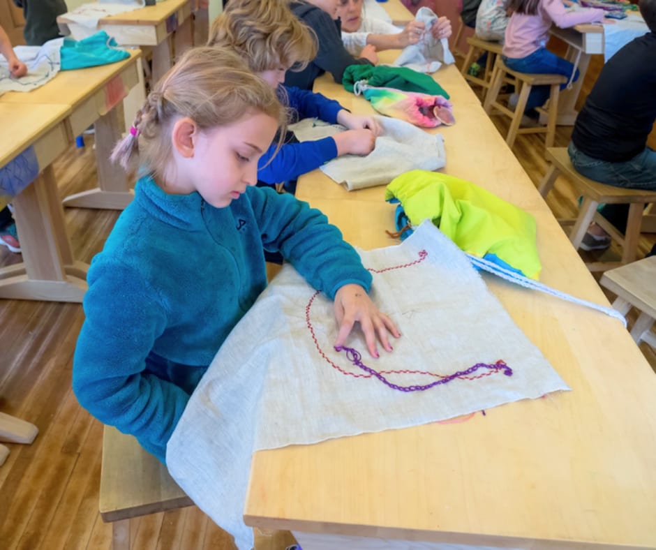 A student sewing by hand at her desk