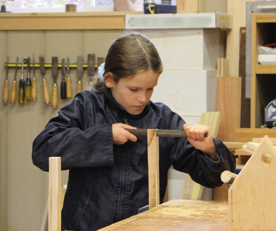 A Waldorf student using a hand tool at the woodworking bench