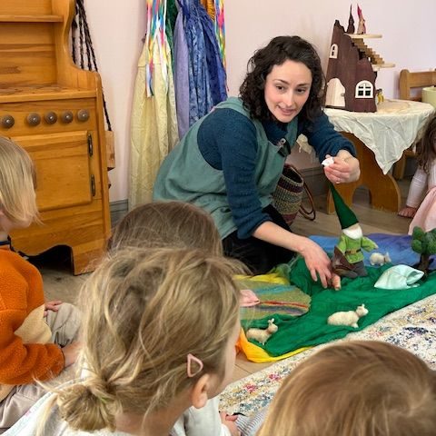 A teacher and young children gathered at a table by the nature table
