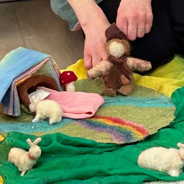 A handmade puppet play set up with felt figures on colored silks