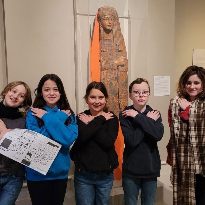 Students posing beside a sculpture in a museum gallery