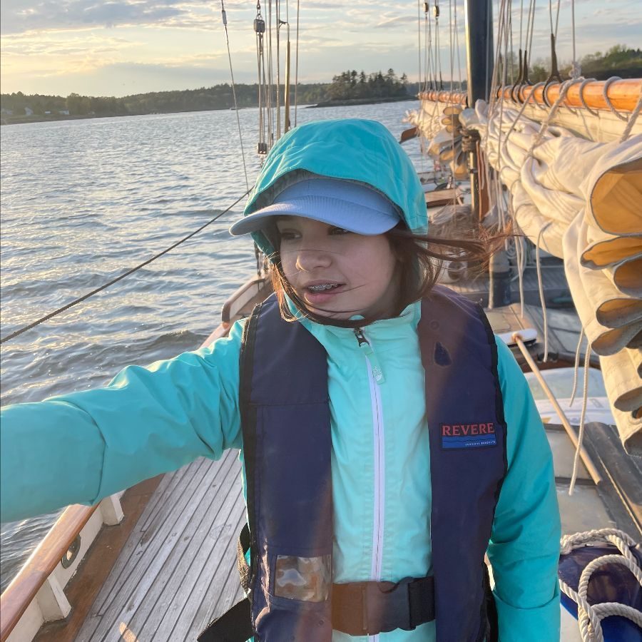 A student in a sun hat and life vest aboard the boat