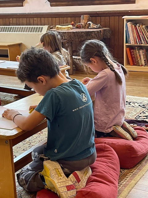 Children kneeling at low desks doing focused main lesson work