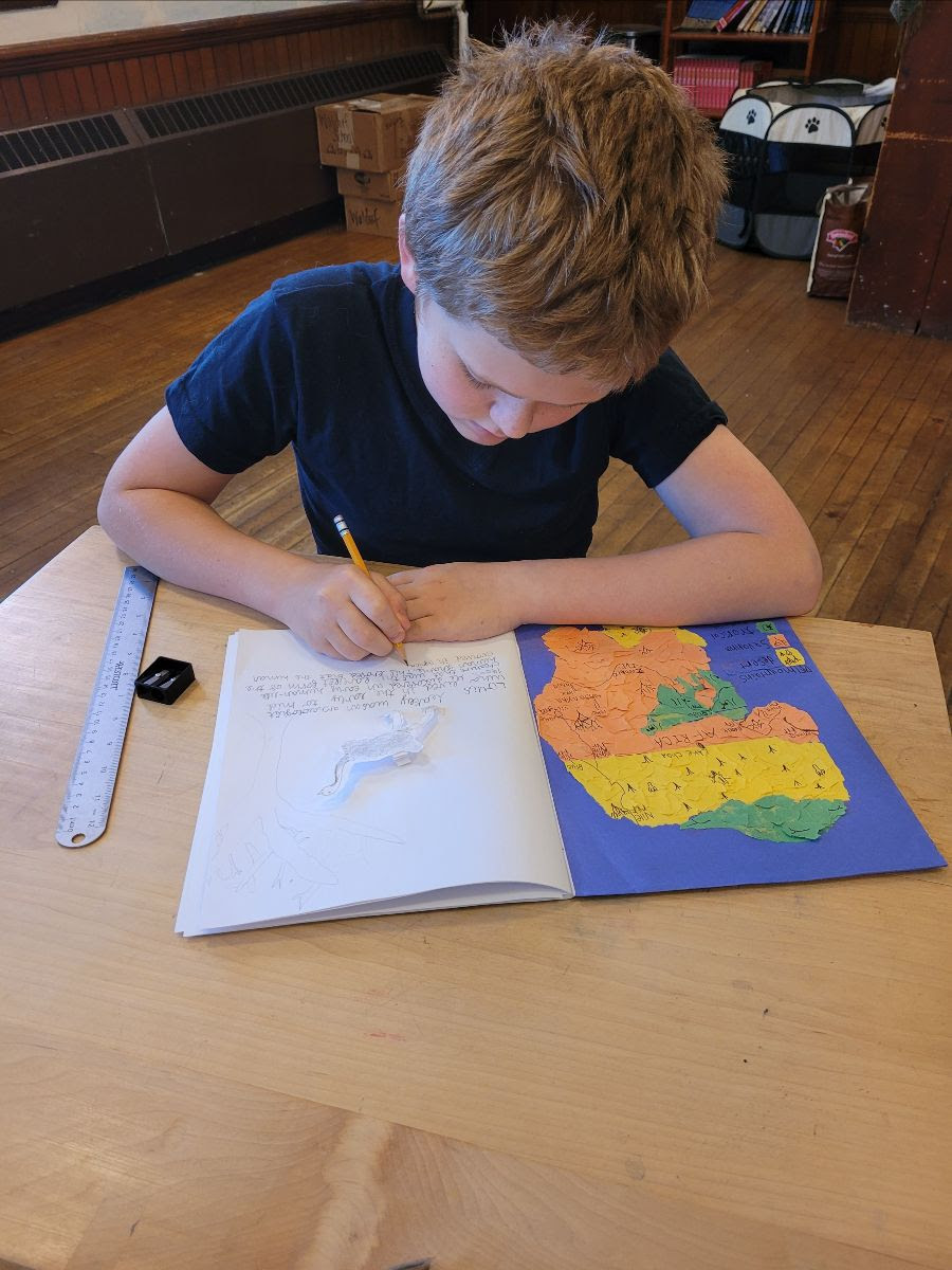 A grades student writing and illustrating a map in his main lesson book